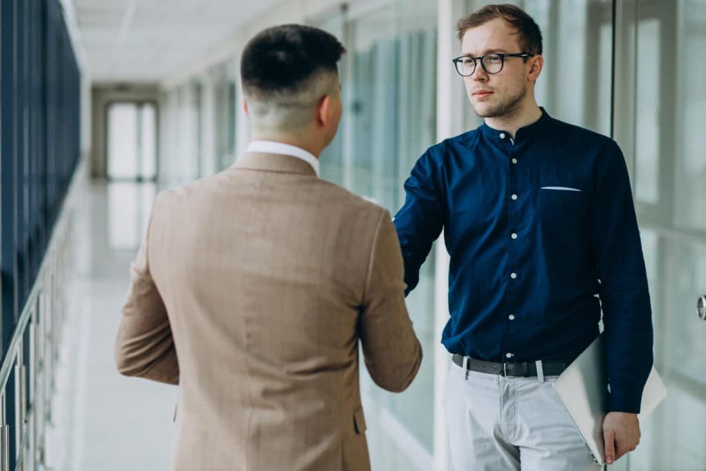 Two male partners shaking hands at the office - image by senivpetro via Freepik