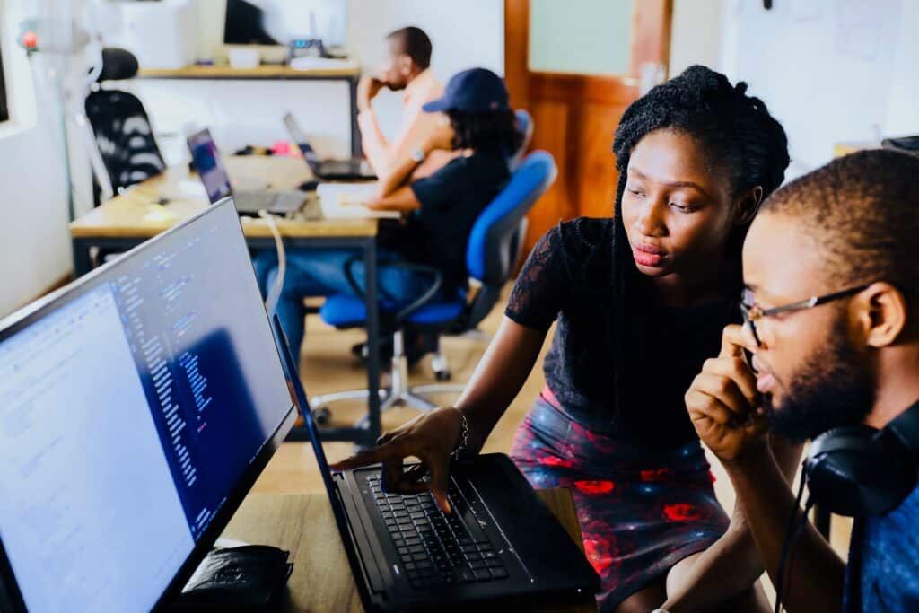 woman and man sitting in front of monitor doing code review, Photo by Desola Lanre-Ologun on unsplash
